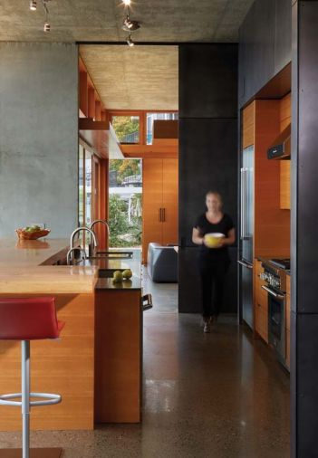 In the kitchen, the cabinetry is made from vertical grain fir, while the darker material around the perimeter of the cabinetry is blackened steel.