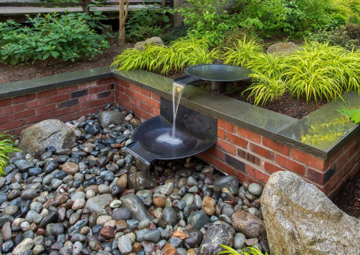 Water flows down the tiers of spun copper bowls and disappears in a cistern under pebbles where it recirculates back to the start of the sequence. A waterproof up light provides drama at night.