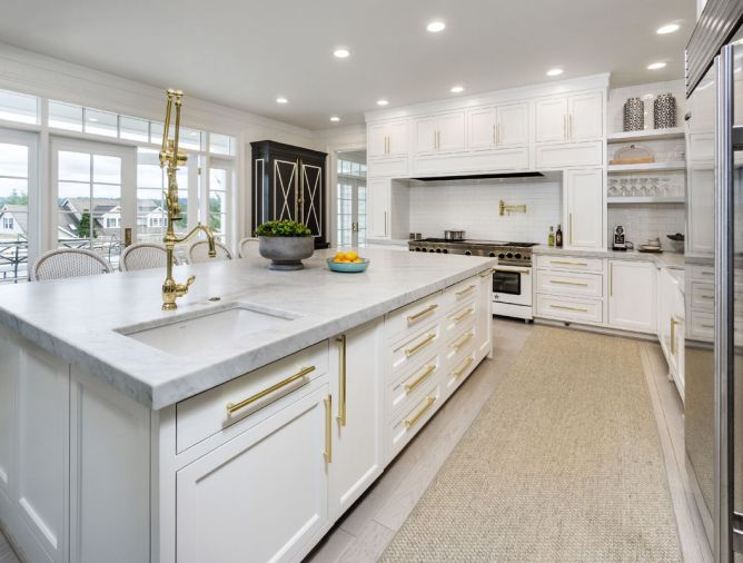 A Blue Star custom range from Eastbank Contractor Appliances takes center stage. Subway tile, Carrara marble, and classic cabinets combine with stainless steel appliances and brass hardware in a twist on tradition. A spacious island forms the kitchen’s epicenter. 