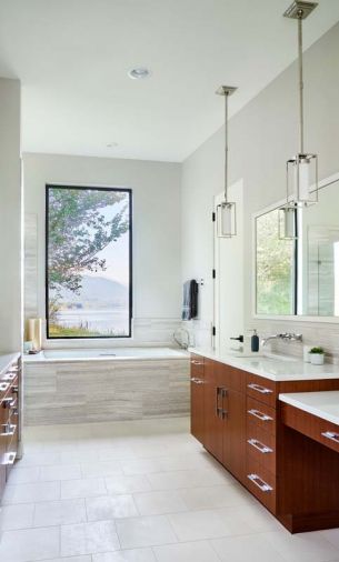 The subtle master bathroom design scheme draws the eye out toward the beautiful view of the lake and the mountains. Vein cut limestone from Intrepid Marble and Granite provides softness and depth to the large soaking tub surround.