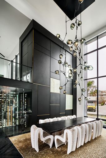 Collaboratively-designed 19' black metal and blown glass chandelier by Keir Legree of Savoy Studios. White Seatbelt dining chairs and Live Edge dining table by Phillips Collection. West Coast Wine Cellars glass-enclosed, temperature-controlled wine cellar stores up to 400 bottles. Feizy custom rug.