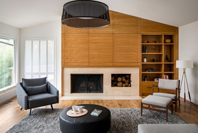 The living room is anchored by a new wood-wrapped fireplace wall with built-in shelving to display the family’s collected items. To “ground the bright, voluminous space and lower the seating area to a cozier human scale,” explains designer Allison Larsen, she added a black Solis Drum pendant light from Pablo that mirrors the round ottoman below.