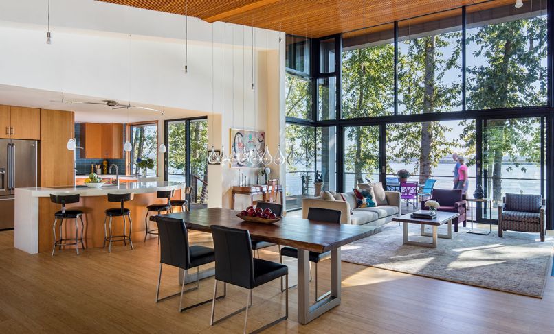 Dyar frames the great room’s expansive river view through Fleetwood’s Thermally Broken Aluminum windows and “probably best on market for price range” large sliding glass doors. Warm Douglas fir 16' ceiling features hanging single bulb SoCo LED pendants which help mitigate the height. Eight Larme ET2 pendants are suspended over dining table. Elite Woodworks fir kitchen cabinets are Dyar’s design. Tech Lighting’s Alina Pendants hang above kitchen island.
