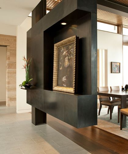 A very sculptural cold rolled blackened steel structure – a creative zone at the entry - purposefully interrupts a view through the dining room, while providing display areas for the homeowners’ treasured painting by Colorado artist Ingrid Magidson, and an equally sculptural plant. Photo © Rob Perry