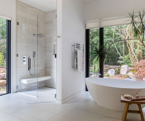 Mosa porcelain tile lines the bathroom floors. Pictured here is the ground-floor master bath, with massive walls of glass framing forest views. The master bath includes a Badeloft freestanding tub and Aquabrass fixtures.