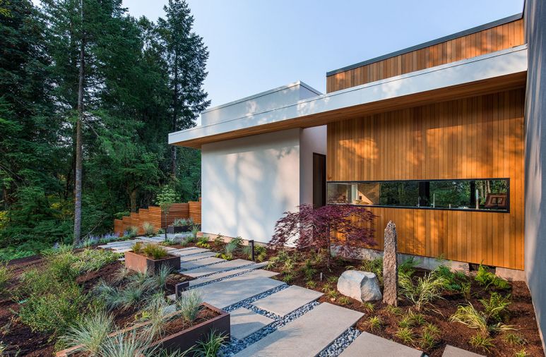 The outdoor walkway that connects the patio to the master bedroom. The exterior is clad in traditional stucco and tongue-and-groove vertical cedar siding.