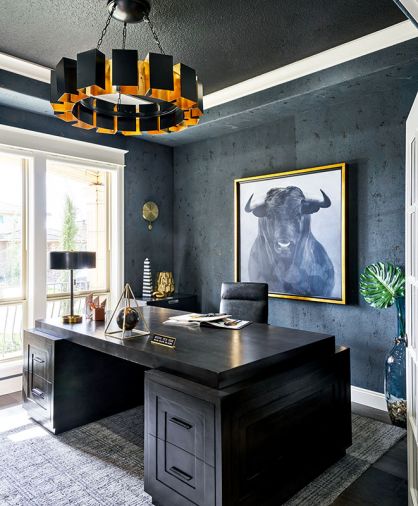 The husband’s office walls heavily textured masculine-feel by Bravura Finishes. Arteriors chandelier echoes brass glow. Bullish thematic artwork by Leftbank; desk by Noir.
