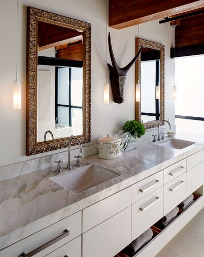 A South African mask purchased during the couple’s travels to that country bisects the master bath’s dual vanity mirrors. Calacatta Caldia slab countertops.