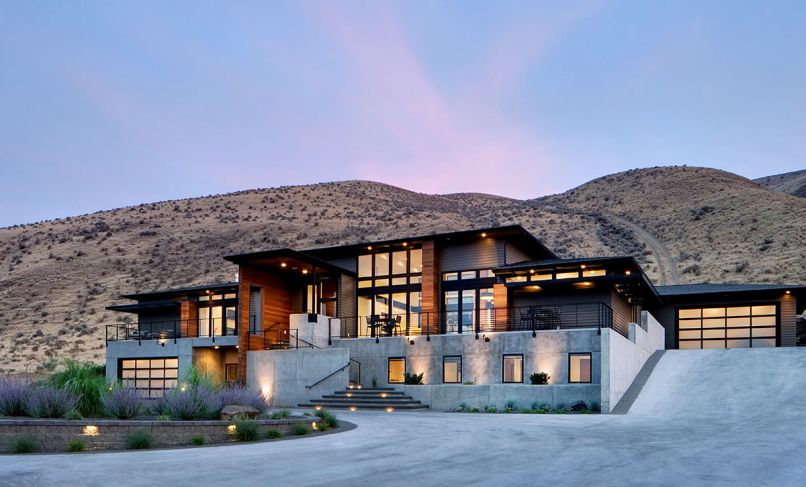 Tucked into the Badger Mountain foothills, this 5,000 sq. ft. linear Pacific Northwest modern home with Pagoda-like roof and deep overhangs sits perpendicular to the slope with expansive views in two directions. Eschewing the usual daylight basement styles found locally, architect Taylor Callaway designed a concrete and stucco basement for the blended family’s children bedrooms, then trimmed the setback main floor in clear Western Red Cedar. The entry element has switchbacks and geometric forms to make the trek more interesting.