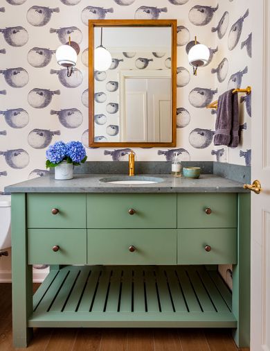 Schoolhouse Electric sconces feature decorative electrical cords and brass rods. Kohler Purist fixtures tie back to original brass door hardware. Abnormals Anonymous wallpaper; Jura Green Limestone countertop. Ann Sacks tile floor resembles wood
