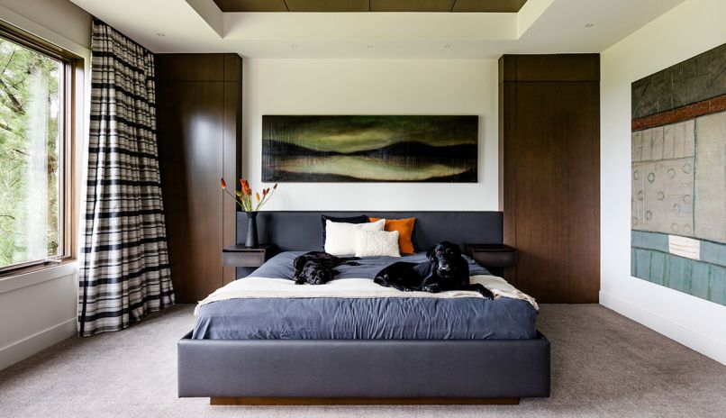 A custom headboard and bed designed to fit between the faux cabinet turned doorway at right and cabinet at left is large enough for the family’s beloved black labs as well.