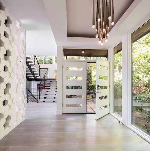 Modular Arts blocks and tiles entry wall echoes home’s hive theme as does the five-glass-slotted custom entry doors. RH Aquitaine entry chandelier highlighted within box beam ceiling.
