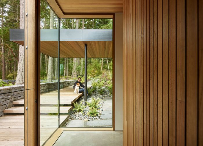 A glass corner in the hallway has a view of the exterior path to the entry, and shows how interior and exterior materials echo one another for easy flow between inside and out.
