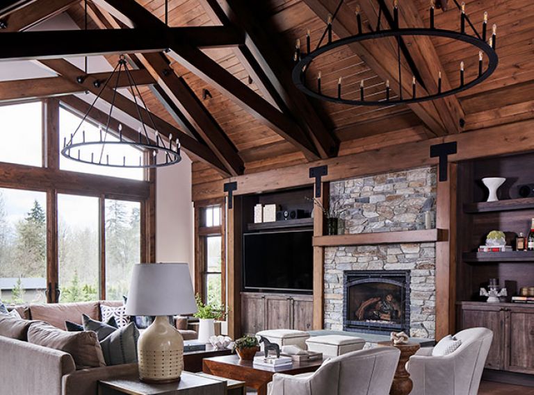 A pair of black iron Pearson chandeliers draw eye to superbly finished beams. Furnishings echo tones of El Dorado Stone fireplace with CR Laine Lincoln chairs in Winchester Vapor Leather and Adriana sectional atop wool Capel rug in Fog.