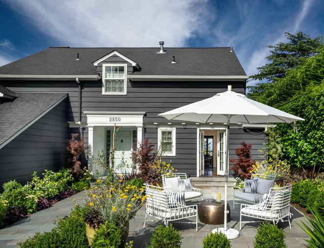 Lord Interior Design gave the home’s exterior bolder paint colors, front door included. Steps up to French door add architectural appeal. Chairs encircle a brass drum coffee table.