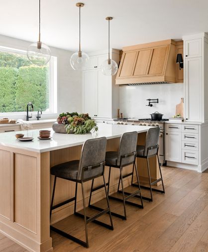 In the kitchen, custom white oak cabinetry bedecked with Restoration Hardware pulls feels furniture-like in the new open plan. A generous island is topped with creamy Pental quartz, and has Lawson Fenning stools tucked beneath. The custom white oak stove hood is the focal point.