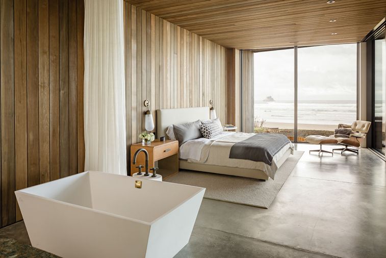 “You feel enveloped in all of the wood,” says Horning of the primary suite, with ocean views via the floor-to-ceiling aluminum windows from Portland Millwork. The freestanding MTI tub enjoys sightlines to the water, as does the custom bed.