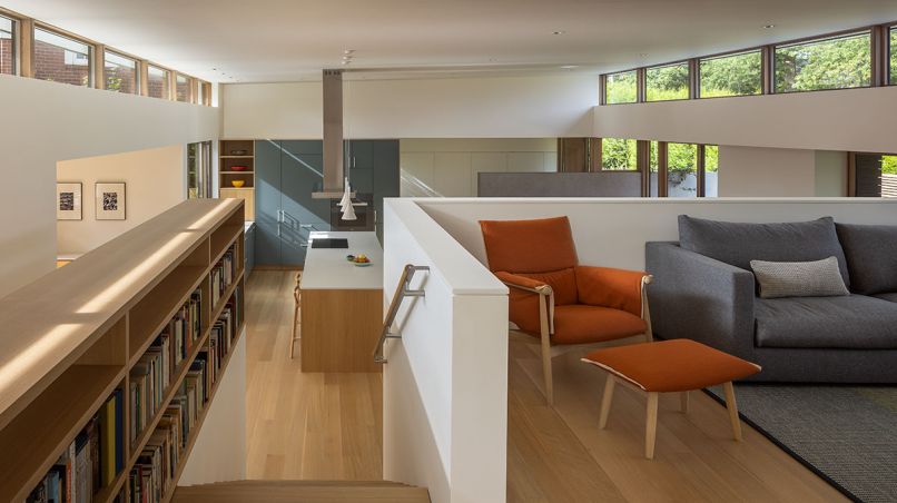 Custom white oak bookcases echoing the rhythm of clerestory windows that flank stairs to family room. Embrace Chair by Carl Hansen and Eoos Magnum sofa by Flex Form.