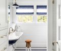Children’s bath features blue custom painted Kohler Brockway 4  wall mounted sink against penny round mosaic floor. Urban Electric sconce painted to match. Custom Roman shades Penthouse Drapery.