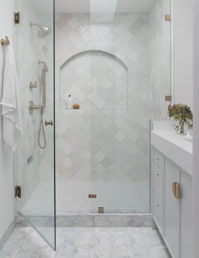 Walls are covered in Cloe Tile, and floors feature white marble mosaic flooring, both from Bedrosians. Brizo plumbing is from Consolidated Supply.