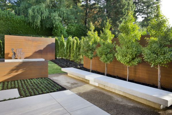 Panels, concrete benches, geometric planting beds and trees with a strong linear line were used to tie the house to the outdoors in a transitional garden space designed by landscape architect Andrea Cochran.