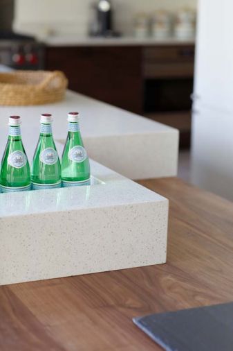 On the island, the quartz work surface was sculpted to provide a self-draining ice bucket or a planter box; when not needed the opening can be seamlessly covered with a matching quartz slab. Quartz has become increasingly popular among designers and homeowners because of its easy maintenance, durability, and stain and heat resistance. Resins bind natural quartz and pigments to create an endless array of colors in several finishes that can then be molded or sculpted to suit the specific purpose.