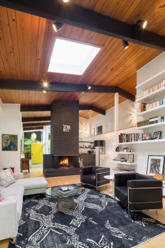 A central fireplace graphically connects the floor to the two-story ceiling and keeps the room to human proportions. The Vanillawood team painted it and the beams black to bring the home’s exterior colors indoors.