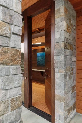 Low maintenance Oregon and Idaho natural stone frames the 10’ walnut entry door from Western Pacific Building Materials, with veneer by Garis Woodworking, Inc., opened here to view the walnut screen wall and Night Water #6 painting by Leigh Li-Yun Wen.