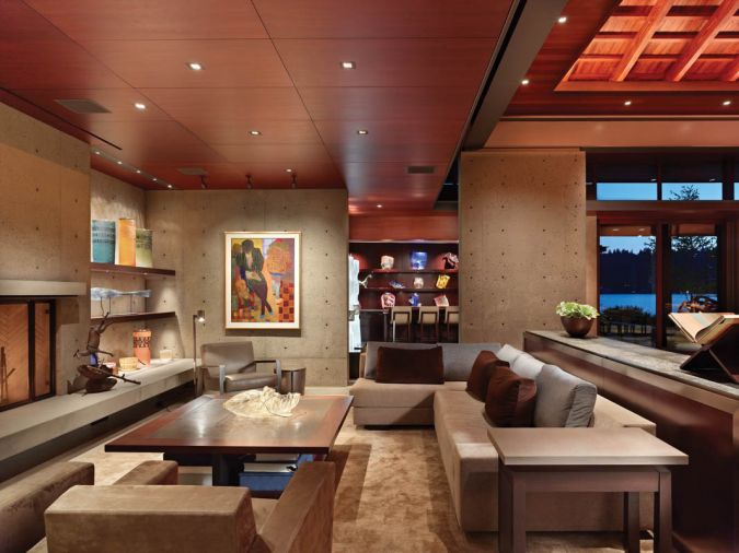 A seating area features several Holly Hunt furnishings, including the New Linden Lounge chair, two Barnard chairs, a Zanzibar table and custom version of her sectional. Chihuly glass lines the shelves of the bar at back.