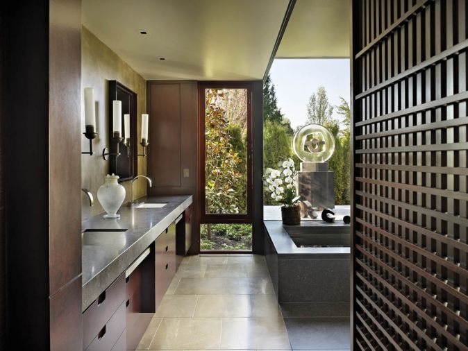 The master bath, which Olson collaborated on with designer Garret Cord Werner, features honed Cambrian black granite countertops with modern, sleek candle sconces. Werner designed the Japanese inspired screen to provide a filter to the walk-in closet.