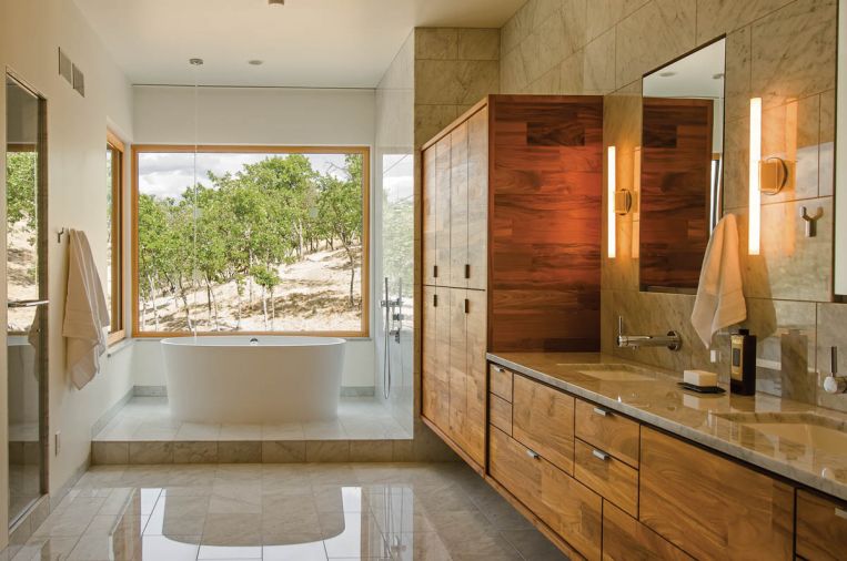 The bathroom floor and walls are made from Carrara marble. At the end of the bathroom, the tub is situated to provide a view of the surrounding forest. Instead of a traditional faucet, the water falls from the ceiling in a thin tube of water, carefully plumbed so as not to splash. Most of the lighting in the home is LED. Green Hammer reports that LED lighting has improved dramatically over the last several years, and they no longer need to rely on imported products to get the correct lumens and color temperature.