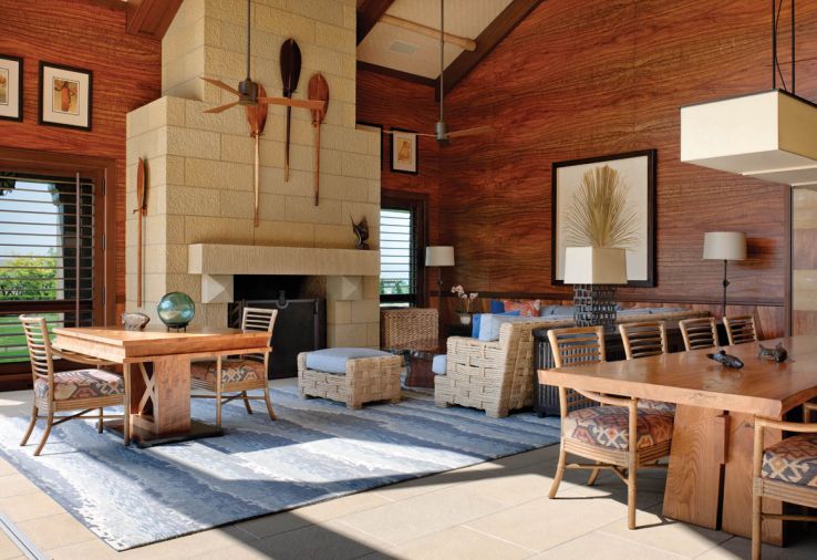 The former garage/utilitarian space is now a beautiful retreat, with precious Koa wood walls and wood-saving wainscot that add drama and warmth. A Himmel sectional pairs with a blue area rug by Hokanson. Table lamp by Gregorius Pineo. Large Douglas fir logs were laid on the ground, and then shaped with a motorized hand planer to resemble the sketches that Rod Knipper provided, before wrapping the ends in hemp rope. Mahogany beams are interrupted by ceiling bamboo mats.