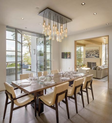 Because of the narrow zoning envelope, the dining room and kitchen are joined together to capitalize on space. A custom Scott Chico Raskey glass chandelier crowns the Holly Hunt table and chairs.