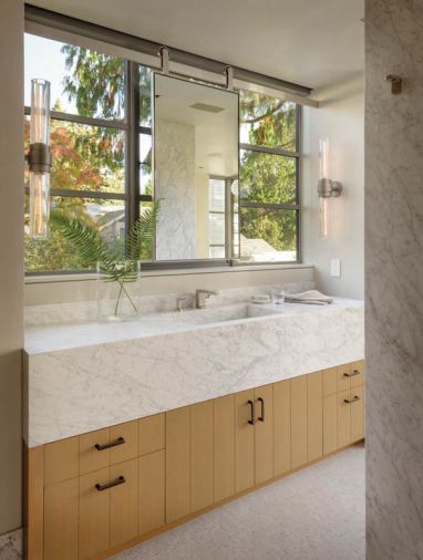 In the master bathroom, Steve Hirt Studio built the tubular sconces. The sliding vanity mirror is by Metal Solutions.