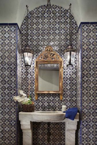 Antique mirror and sconces add shine and light to the powder bathroom’s blue and white hand painted tiles by Mosaic House. Industrial Centro faucet from Old and Elegant in Bellevue.