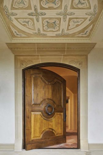The Great Northwest Door Company crafted the arch oak pivot entry door crowned with a hand painted fresco designed by Hyde Evans Design and executed by Cathy Conner of Studio C.