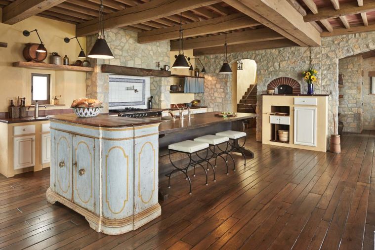 Tuscan architectural methods were challenging for many of the local craftsmen, especially those asked to re-create the appearance of typical late 17th, early 18th century kitchen cabinets that were made from cement or plaster and then fitted with painted wooden doors. The team designed the island to resemble an antique farm table; pendant task lighting designed by Hyde Evans. A very old antique cupboard with original paint abuts the island, mimicking the angle of the wood burning pizza oven set into the rustic stone wall opposite.