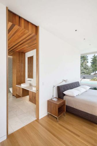 The master bedroom combines textured glass tile on the far wall with wood cladding that extends from the ceiling to the exterior soffit, creating a unique sense of enclosure.
