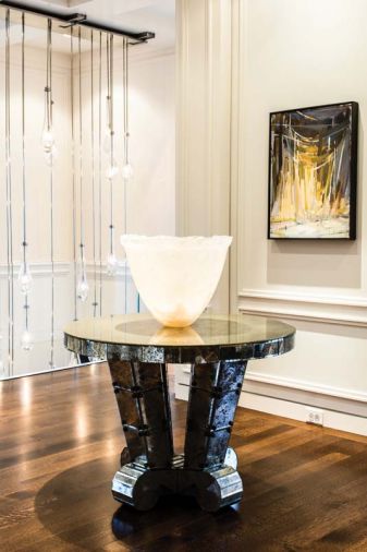 A Jean de Merry “Amalfi” entry table with mercury mirrored glass and bronze accents. Bronze staircase pickets by GCW. Artwork is from the client’s collection.