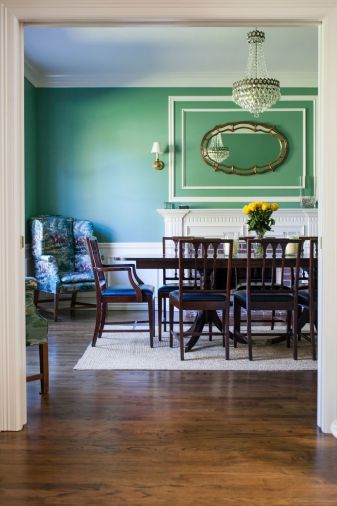 The bold green hue in the dining room was chosen from a collection of historic paint colors, yet it feels very contemporary. The Gishes already owned the easy chair and dining set, but they reupholstered the seats in navy leather for a fresh look.