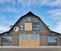 First envisioned as an imposing red metal barn, the new design blends better with the rolling hills surrounding the Lake Chelan countryside.