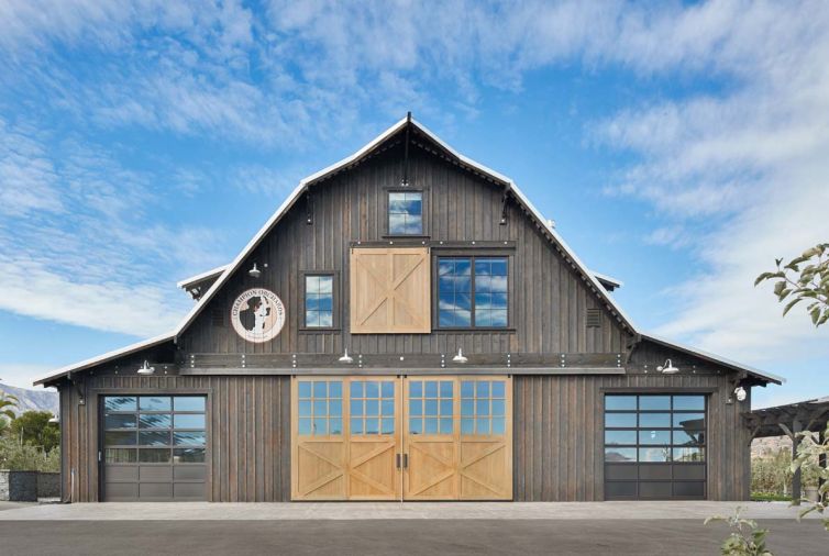 First envisioned as an imposing red metal barn, the new design blends better with the rolling hills surrounding the Lake Chelan countryside.