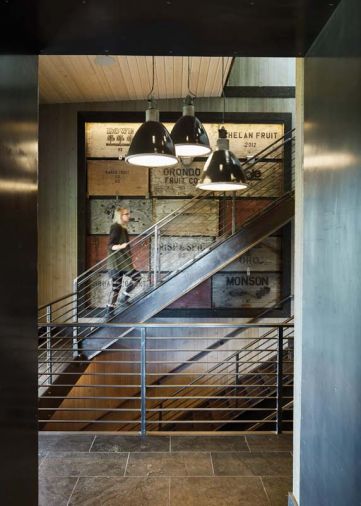 Barnes Welding constructed the three-story steel staircase with wood treads; SkB recommended the vintage apple crate as a unifying element that ties all three levels together.