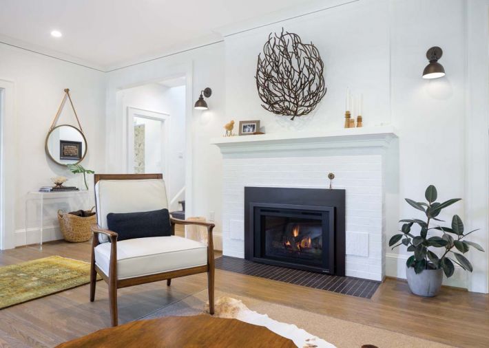 The couple’s dark iron coral piece adds visual contrast to the original fireplace surround and mantel painted with Benjamin Moore Simply White. The sconces are from Schoolhouse Electric.