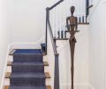 The original dark stair with enclosed railings was gutted and replaced with a wider, repositioned one. The staircase railing and custom tapered newel post add contrast thanks to Benjamin Moore s Iron Mountain.