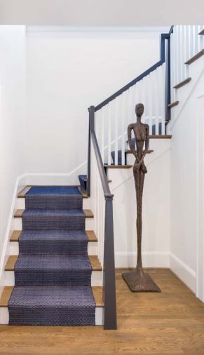 The original dark stair with enclosed railings was gutted and replaced with a wider, repositioned one. The staircase railing and custom tapered newel post add contrast thanks to Benjamin Moore's Iron Mountain.
