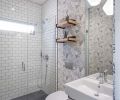 A wall mount sink and toilet with in-wall carrier system helped to maximize the limited space in this new main level full bath, which replaced an original powder bath in poor shape. The field tile in the shower is from Dal Tile. The floor tile is Straturra Hex from Ann Sacks.