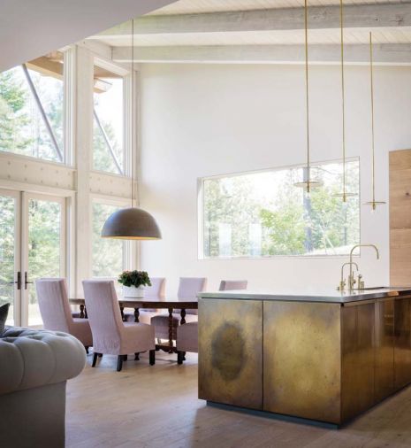 “DMA built the brass panels and was instrumental in developing the finish, which allows the material to breathe and evolve over time,” says Byskiniewicz. The dining room light fixture by the Italian company Il Fanale is 31.5” in diameter. Made of steel with gold leaf interior, it casts a warm glow over the dining table. A new horizontal window frames the mountainous landscape.