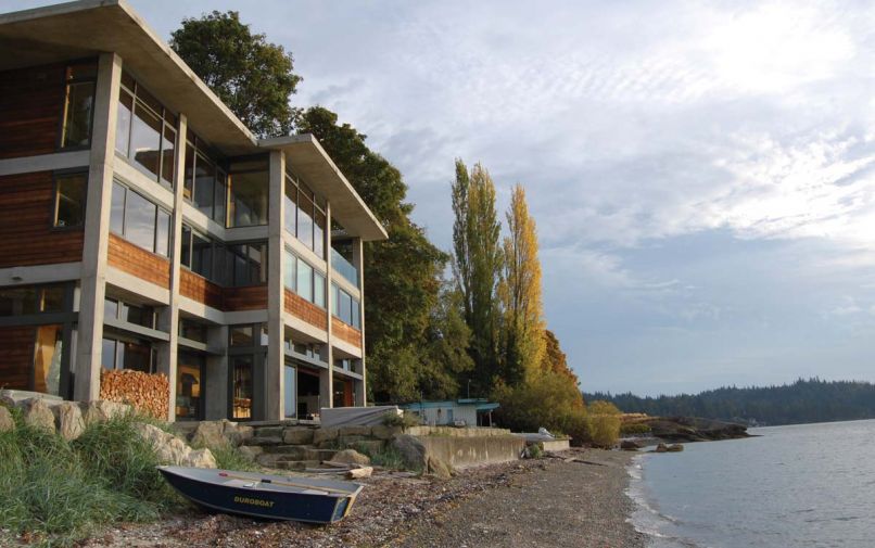 On the seaward side, expansive windows, inviting outdoor living spaces, and a waterfront patio invite visitors to step directly into the landscape.