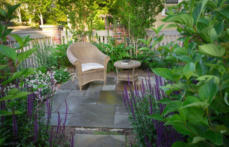 A quiet reading spot was designed to take advantage of the sunniest corner of the garden. The rebuilt fence and plantings provide privacy. Bluestone pavers were used throughout the landscape.